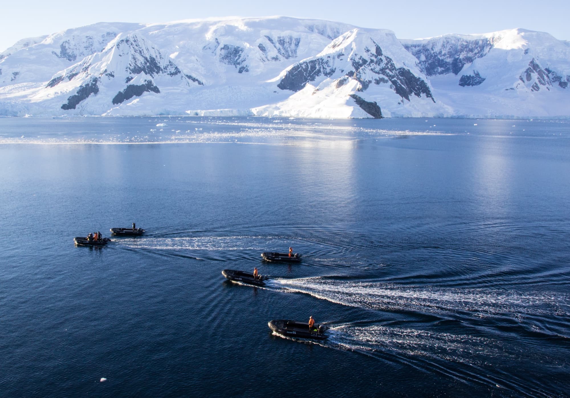Zodiacs crossing Neko Harbour, Antarctica, glaciers behind.