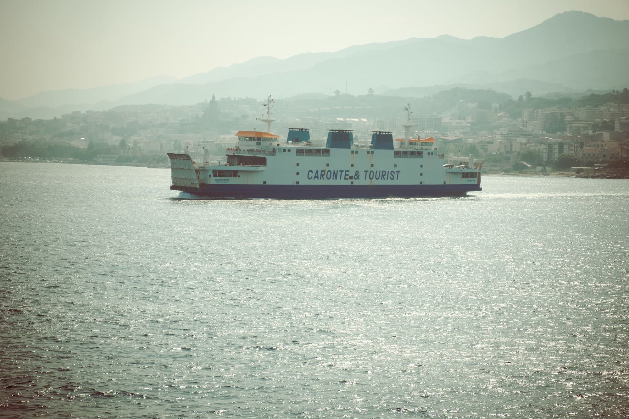 A ferry crossing the Strait of Messina, Calabria's hills behind.