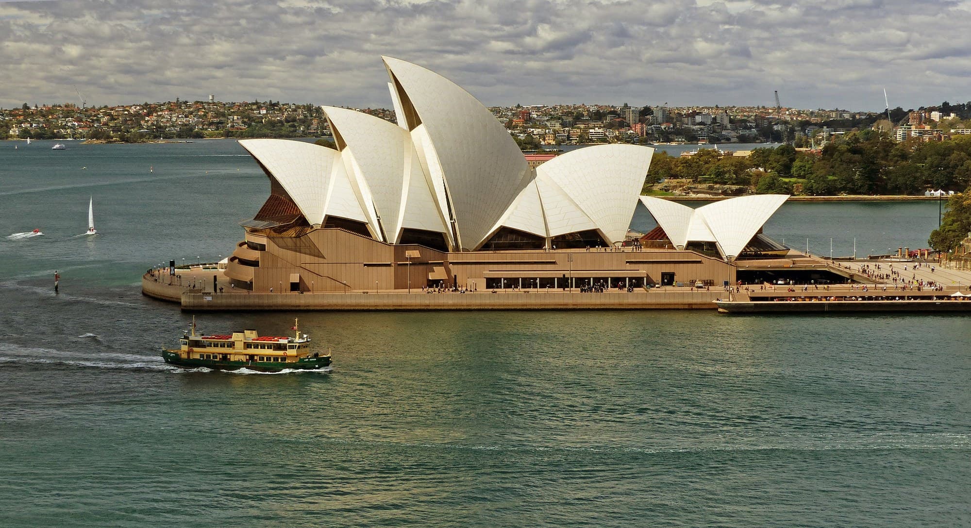 The Sydney Opera House from the harbour, a ferry passing.