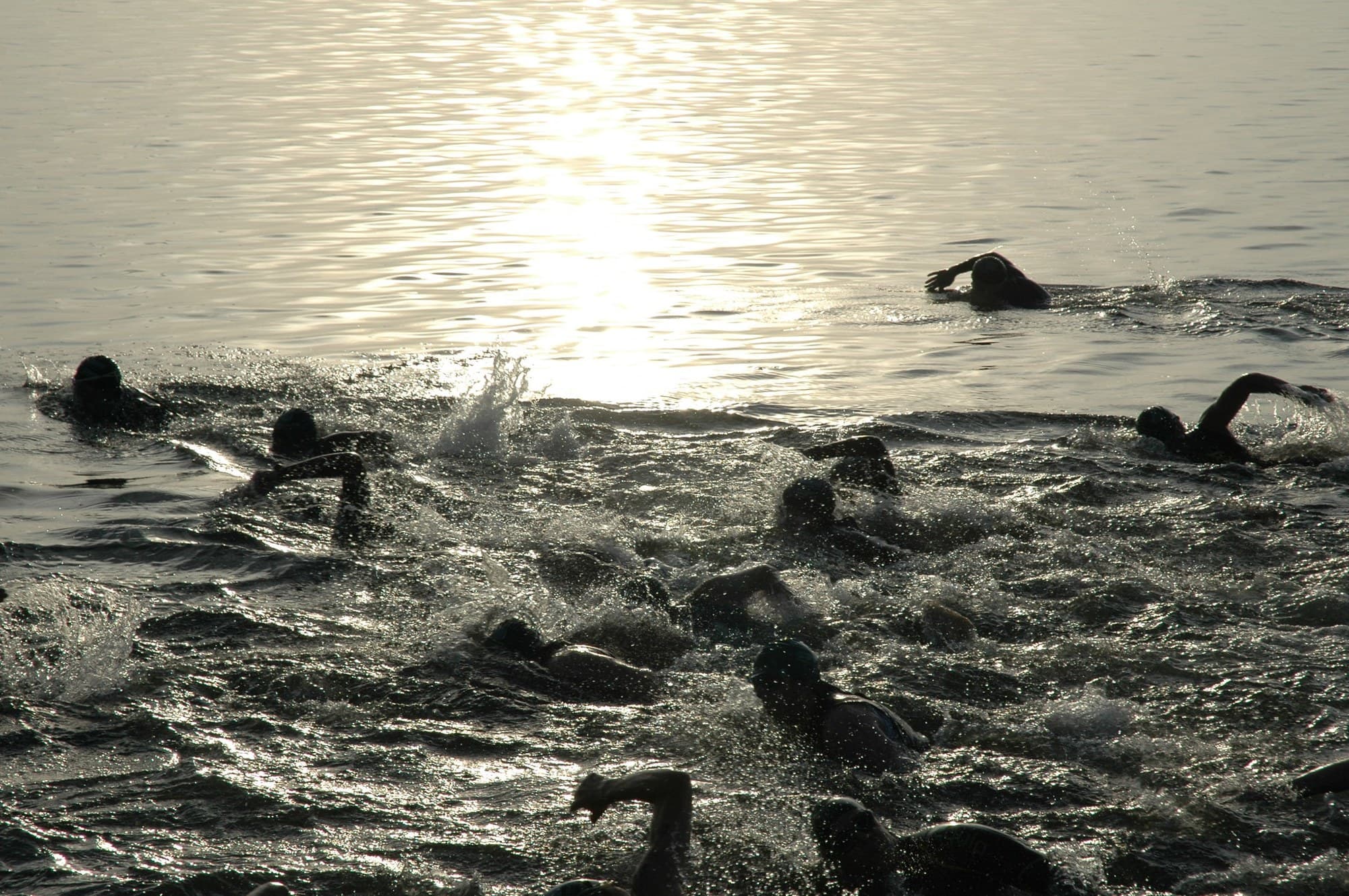 Swimmers in the water at the start of the White Lake half-distance triathlon, early morning light.